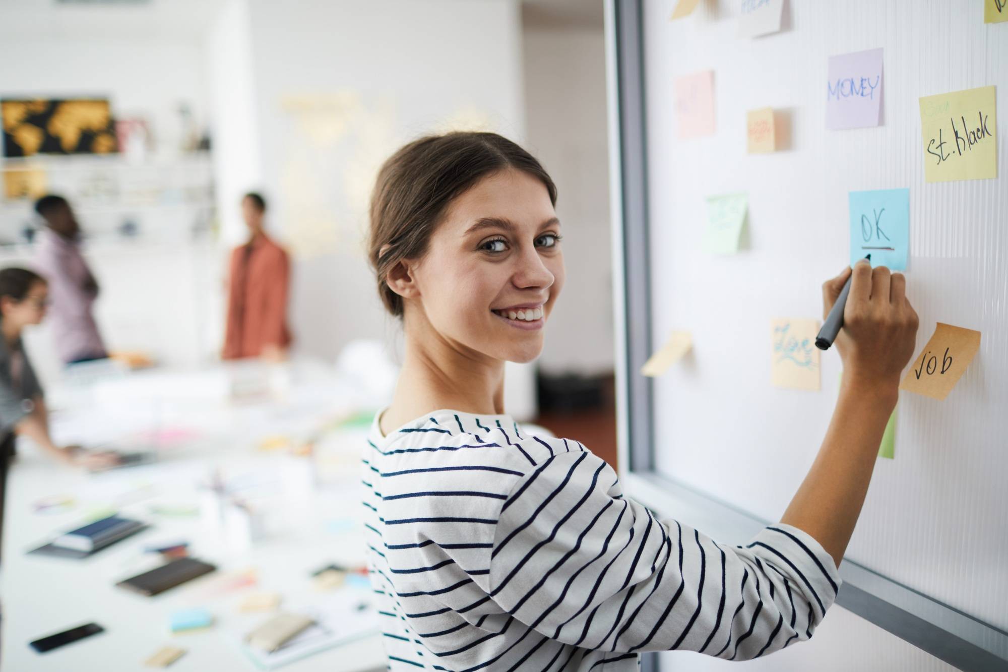 Smiling Young Woman Writing on Board